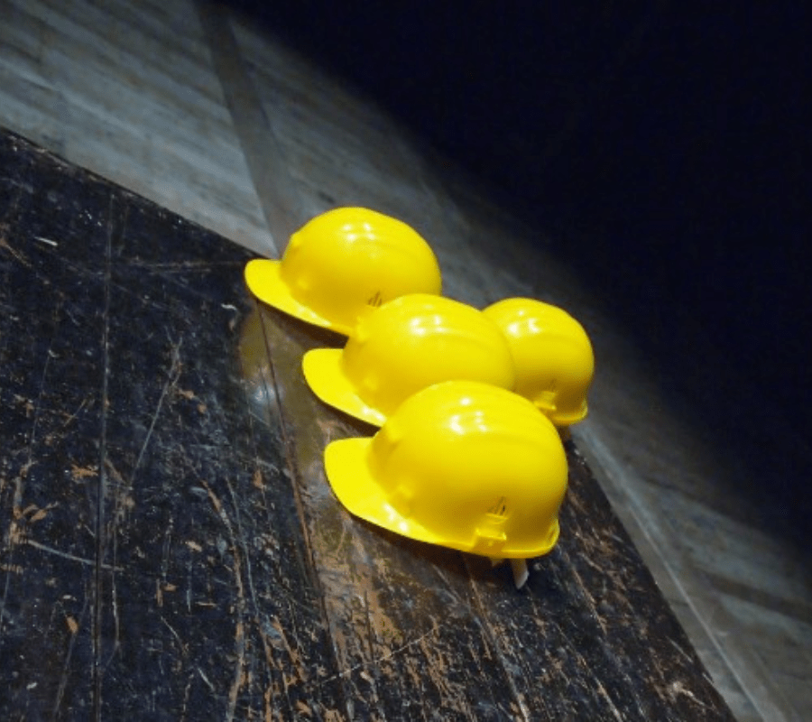 Four yellow construction hard hats on a wooden table showing the skills gap in the construction industry.